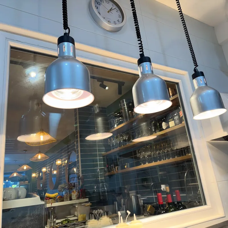 Cocina abierta vista desde el pase, con lámparas de calor plateadas