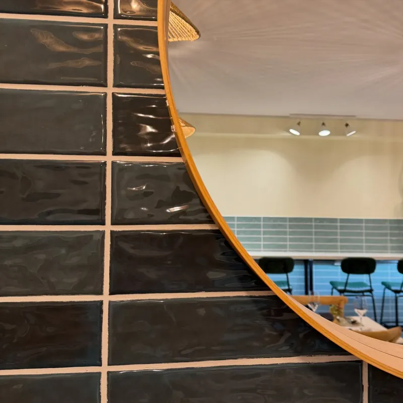 Espejo redondo que refleja el azulejo y el salón