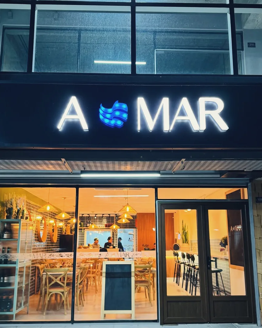 La fachada de A MAR de noche, bajo su letrero luminoso